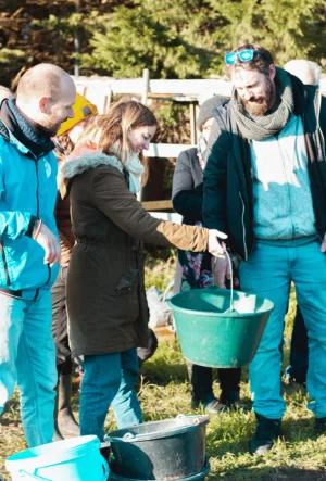 Groupe de personnes sous pesant un seau de composte de toilettes sèches à litière lors de la formation toilettes sèches